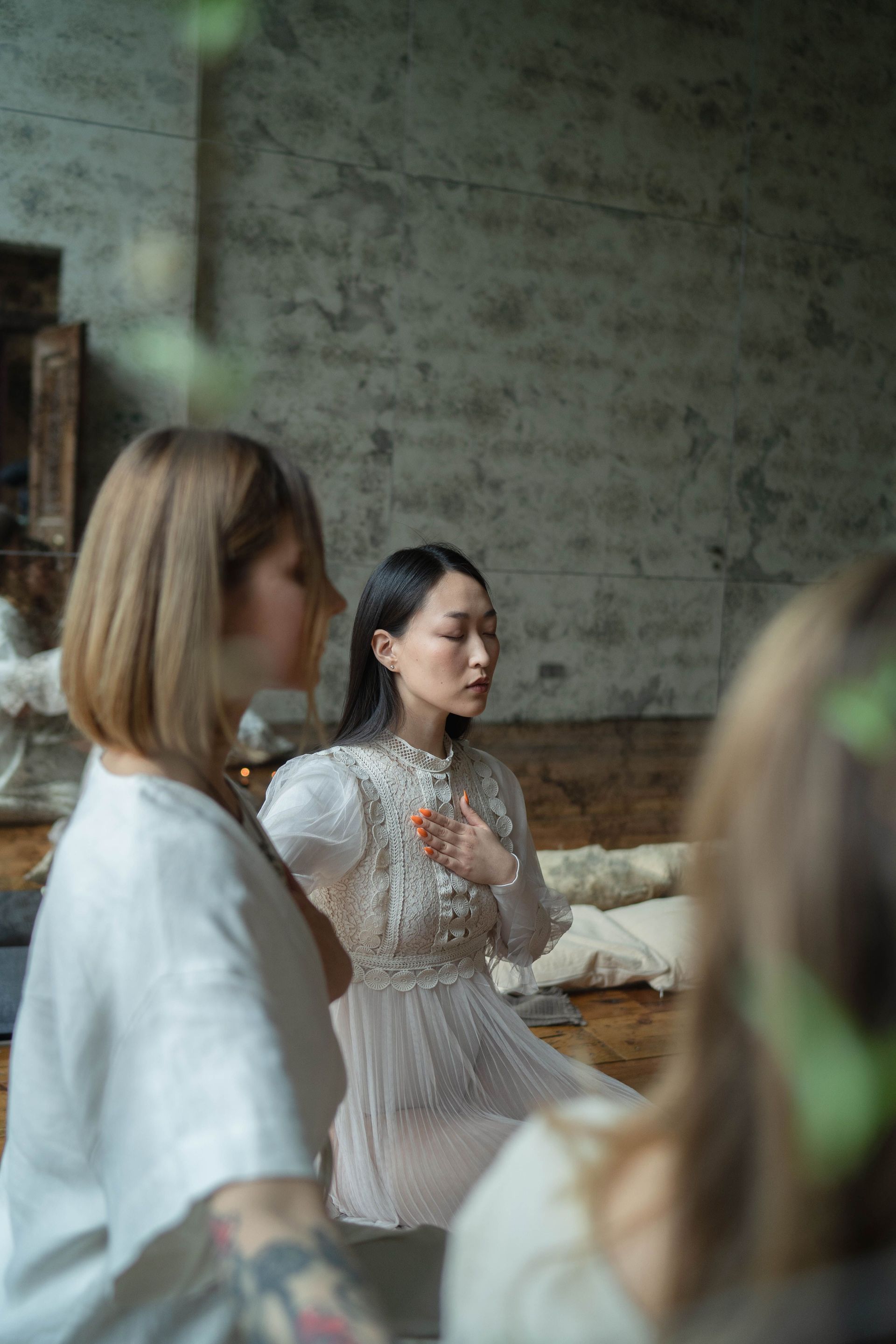 A group of women meditating peacefully in an indoor setting with natural tones.
